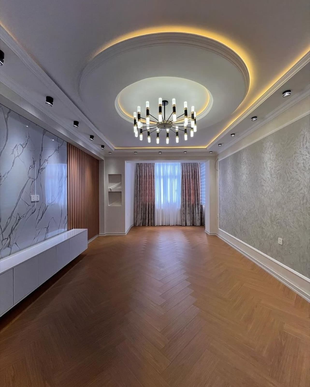 Living room with herringbone wood flooring, a circular ceiling detail, and a contemporary chandelier