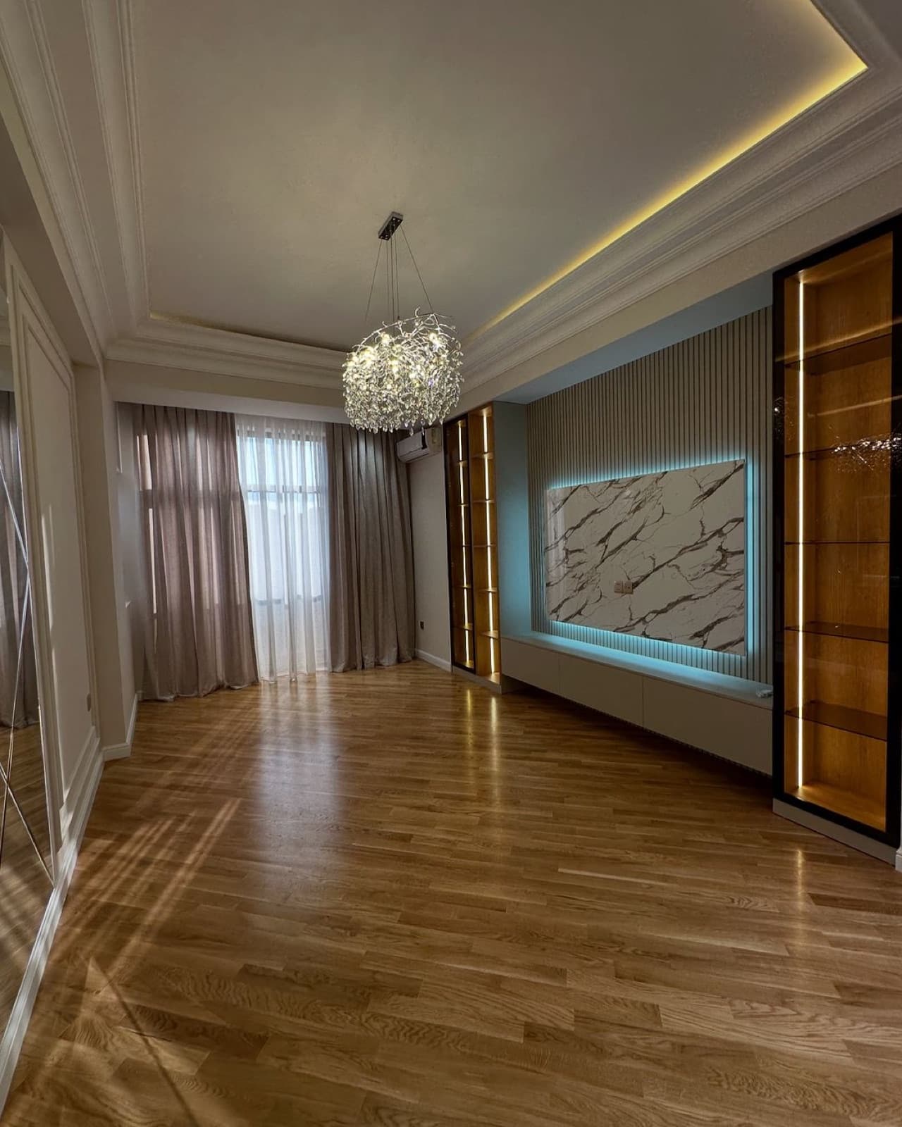 Living room with wood flooring, illuminated wall panels, and a marble-patterned television feature